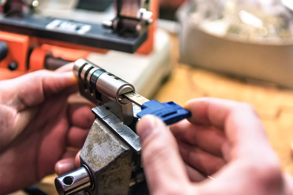 Locksmith servicing a high-security lock cylinder held in a vise with its key