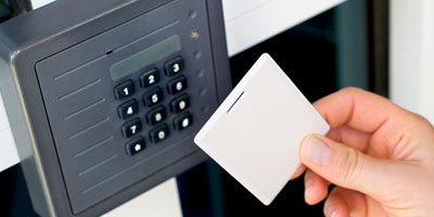 Employee holding a proximity card to a keypad card reader for commercial access control